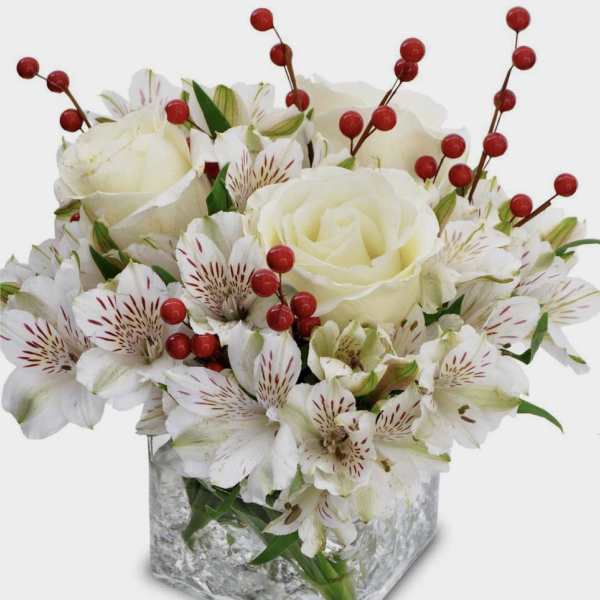 White roses and alstroemeria in a square glass vase with red berry stems