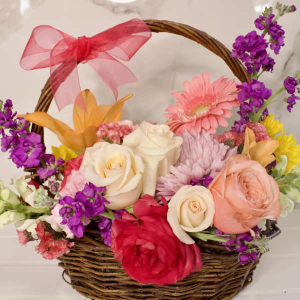 Mixed flower basket with roses, gerbera daisies, and a pink bow