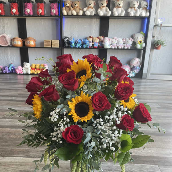 Bouquet of red roses and sunflowers in a glass vase