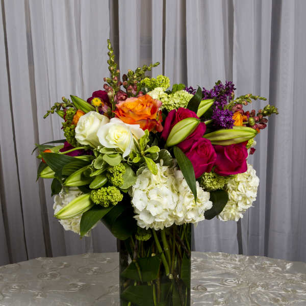 Colorful mixed flower arrangement in a tall glass vase