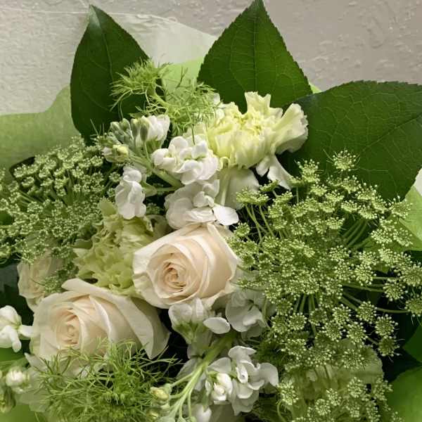 Bouquet of pale roses and white flowers with large green leaves