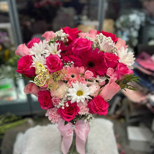 Pink and white bouquet of roses and daisies with a butterfly pick