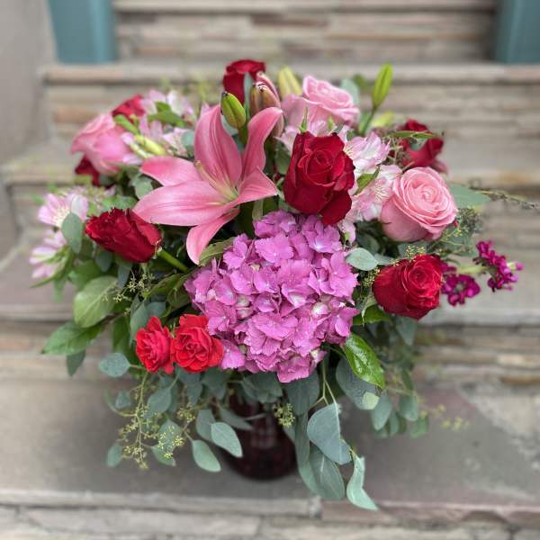 Pink lilies and red roses arranged with hydrangea in a vase
