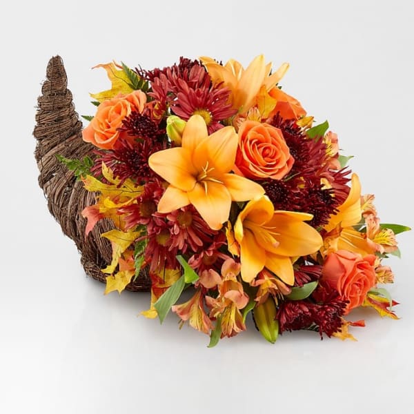 Autumn bouquet with orange lilies and roses in a woven horn-shaped container