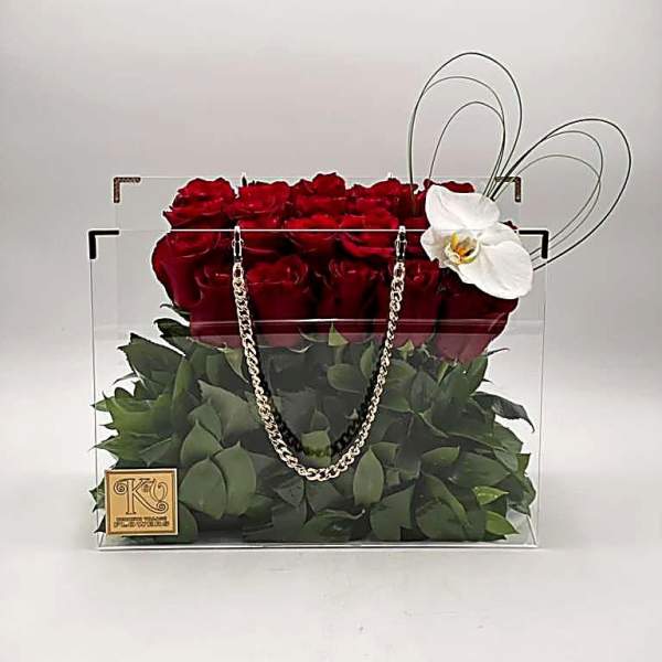 Red roses in a clear square box with a white orchid accent