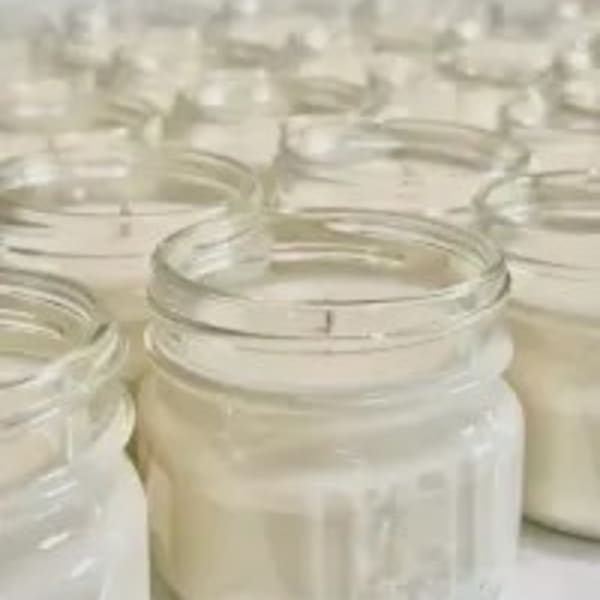 Rows of white candles in clear glass jars