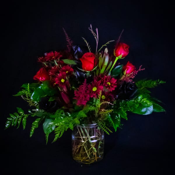 Red roses and magenta daisies in a glass vase