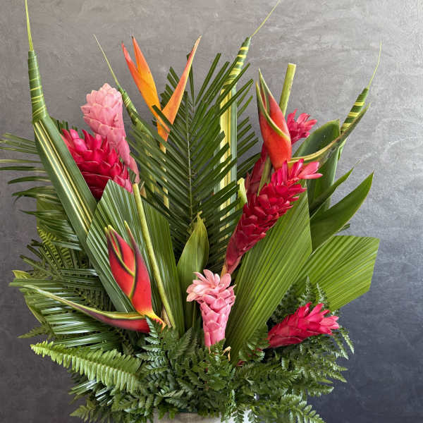 Tropical arrangement with pink and red ginger flowers in a white container