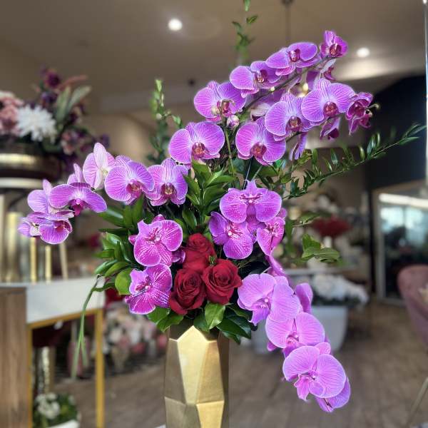 Pink orchids and red roses in a gold vase