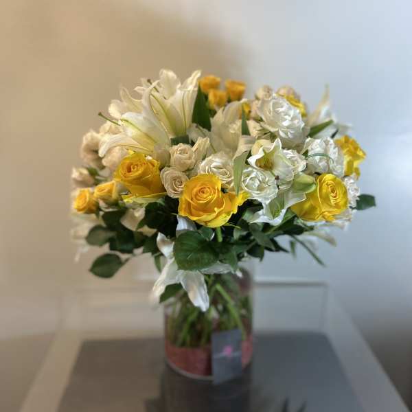 Bouquet of yellow roses and white lilies in a glass vase