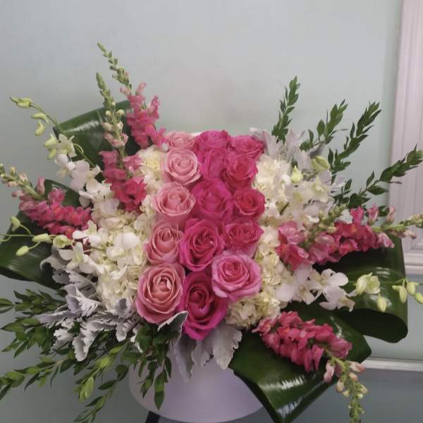 Pink and white rose arrangement with snapdragons in a white vase