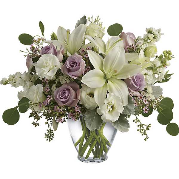 Bouquet of white lilies and lavender roses in a clear glass vase