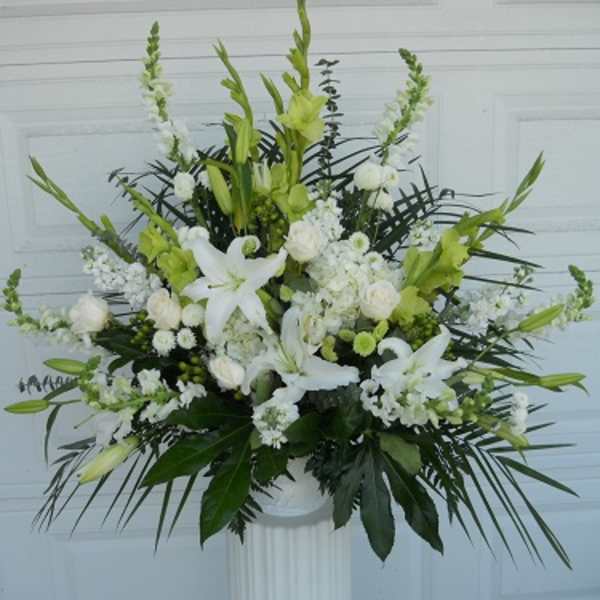 White and green floral arrangement in a pedestal vase