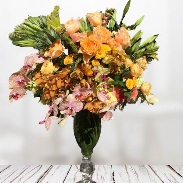 Mixed orange and pink flowers arranged in a tall glass vase