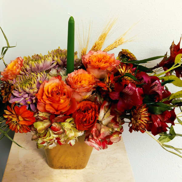 Autumn floral arrangement with orange and red blooms in a gold vase