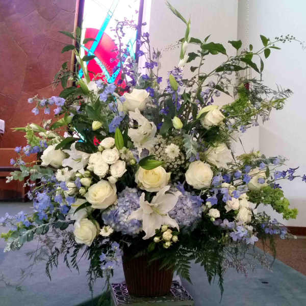 Large white and lavender floral arrangement in a tall vase