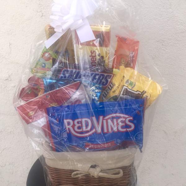 Gift basket of assorted candy wrapped in clear cellophane with a white bow