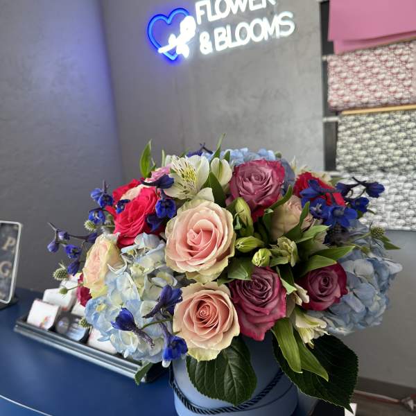 Mixed rose bouquet with blue hydrangeas in a round box