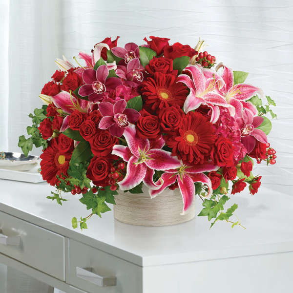 Bouquet of red roses, pink lilies, and red gerbera daisies in a round vase