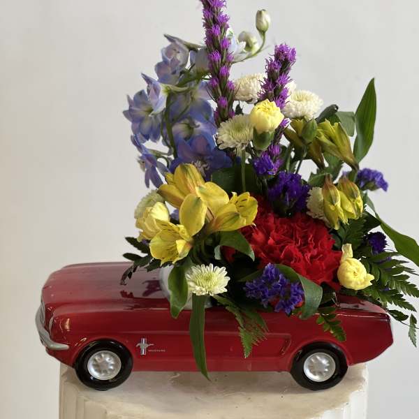Mixed flower arrangement in a red toy car container