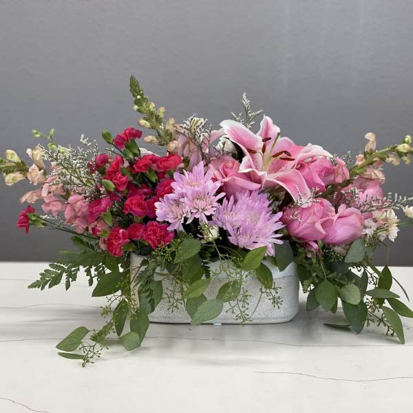 Pink floral arrangement in a rectangular white vase