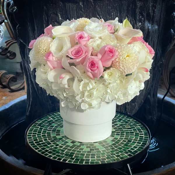 Pink and white floral arrangement in a white hatbox
