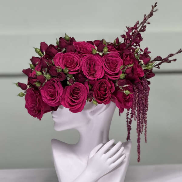 Bright pink rose arrangement in a white sculptural vase with a hand detail