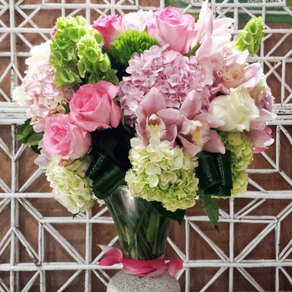 Pink and white floral arrangement in a glass vase with two candle holders