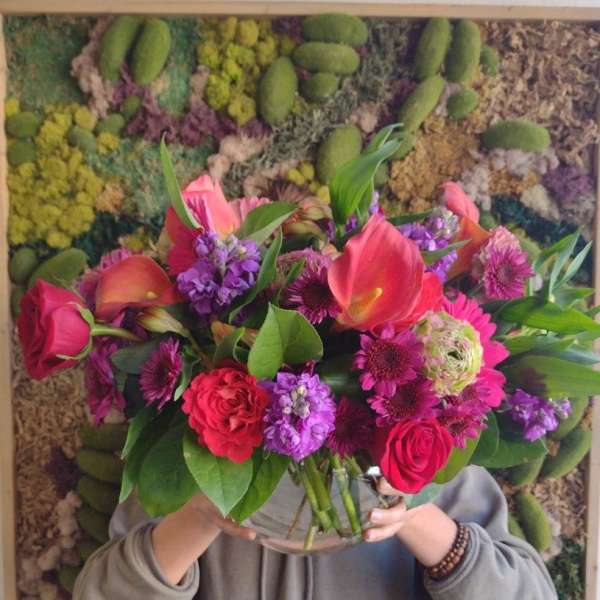 Large mixed bouquet of pink, purple, and orange flowers in a glass vase