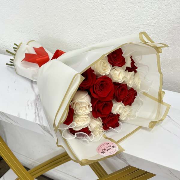 Bouquet of red and white roses wrapped in white paper with gold trim