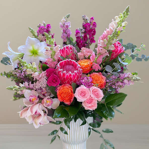 Pink and orange mixed flower arrangement in a white vase