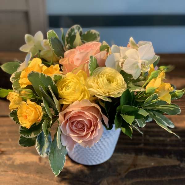 Mixed bouquet of pink, yellow, and white flowers in a white vase