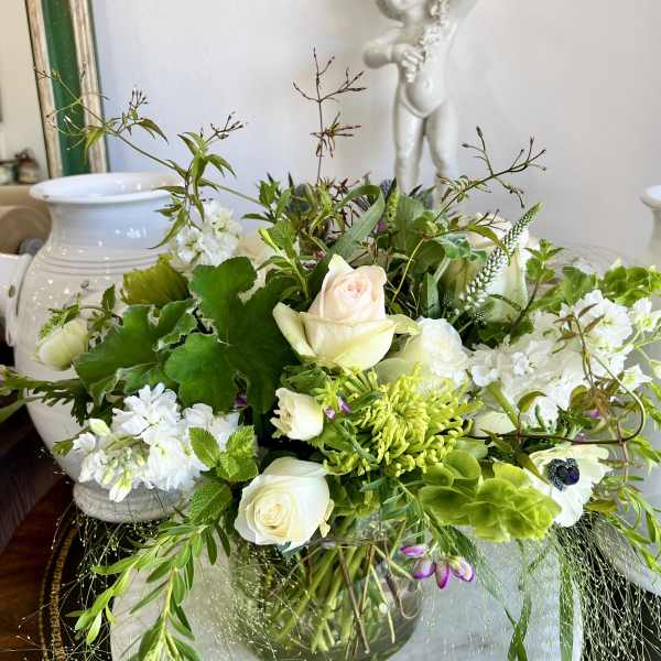White and pale green floral arrangement in a glass vase