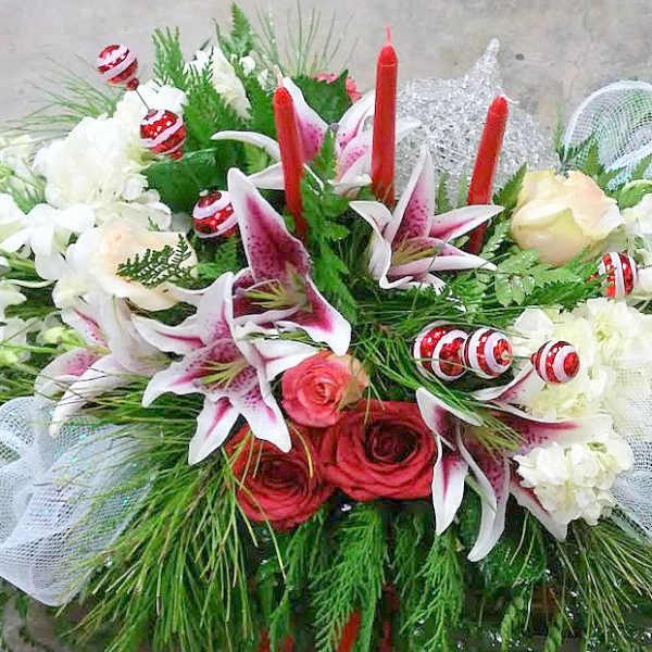 Floral arrangement with lilies, roses, and red candles