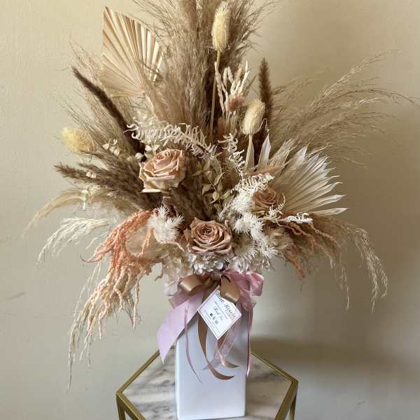Dried floral arrangement with blush roses in a white vase
