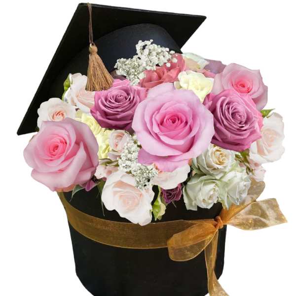Pink and lavender roses in a black graduation cap box with a gold ribbon