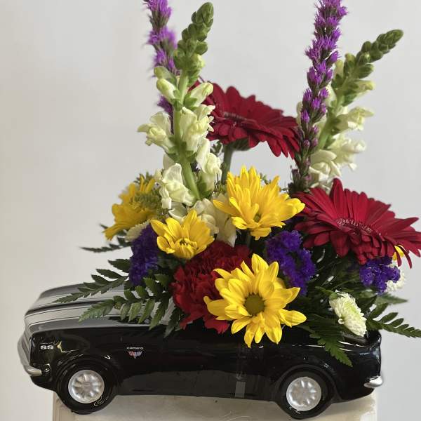 Colorful flower arrangement in a black toy car container