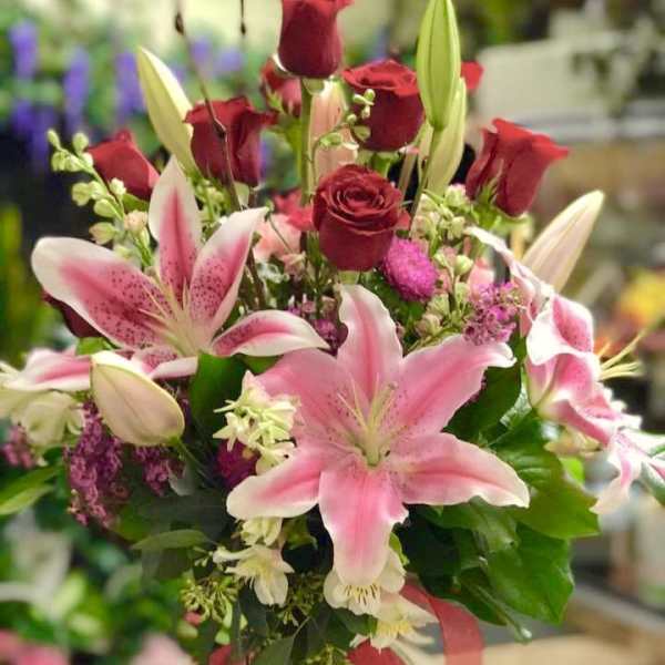 Bouquet of pink lilies and red roses tied with a ribbon