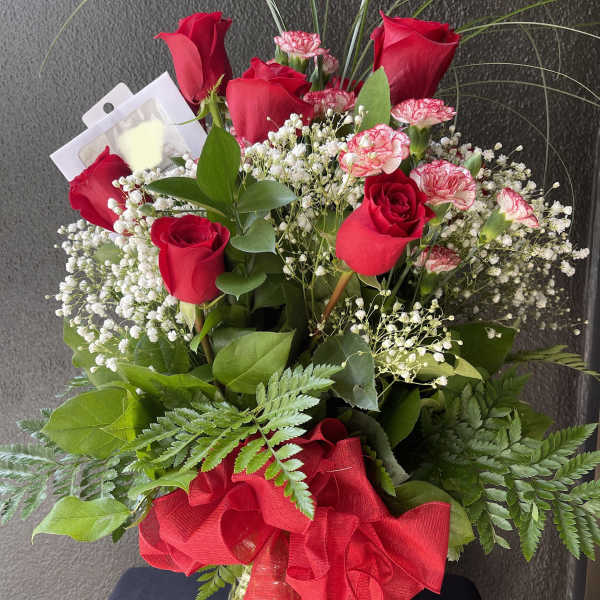 Red roses and pink carnations in a glass vase with a red ribbon