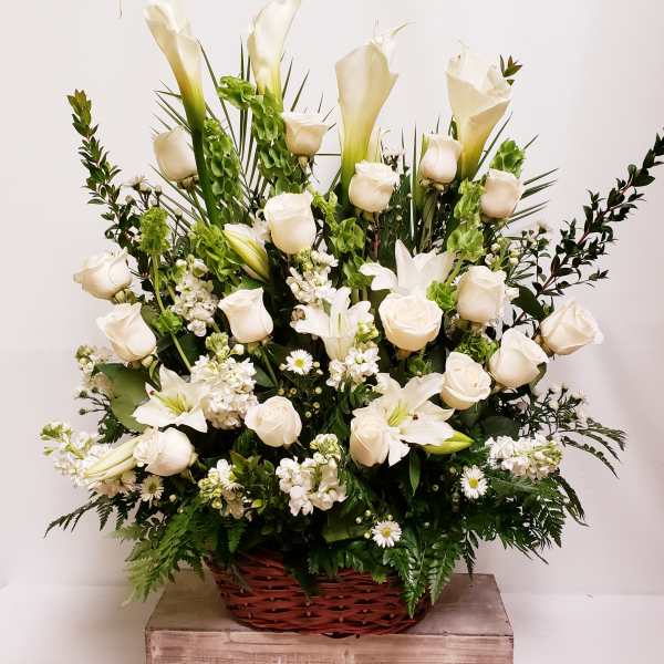 White roses and calla lilies in a wicker basket arrangement