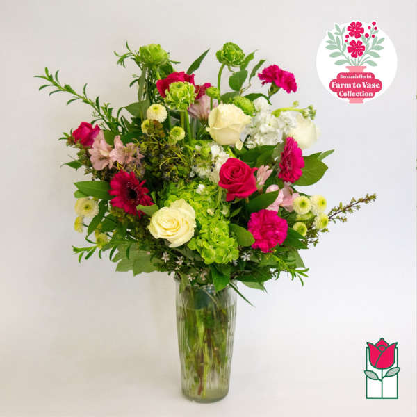 Mixed pink, white, and green flowers arranged in a tall glass vase