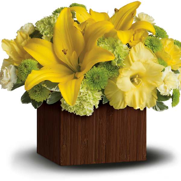 Yellow lilies and green pompons in a wooden cube vase