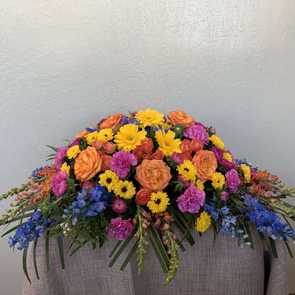 Colorful floral casket spray with orange, yellow, pink, and blue flowers
