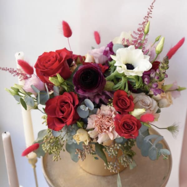 Mixed bouquet of red, white, and pink flowers in a gold vase