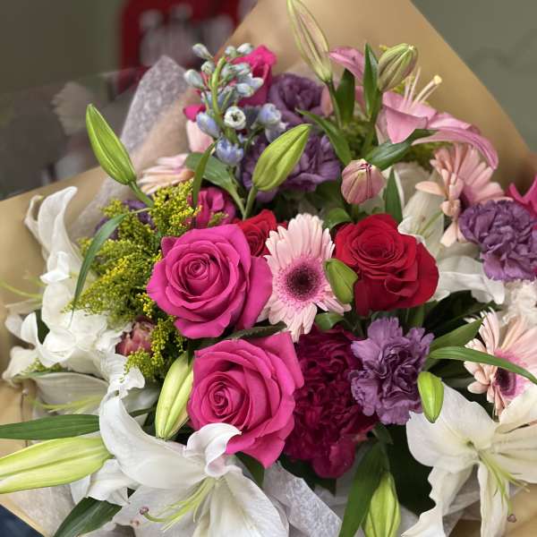 Bouquet of pink and white flowers with roses and lilies wrapped in paper