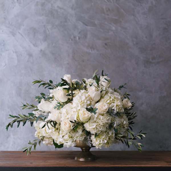 White rose and hydrangea arrangement in a gold pedestal vase