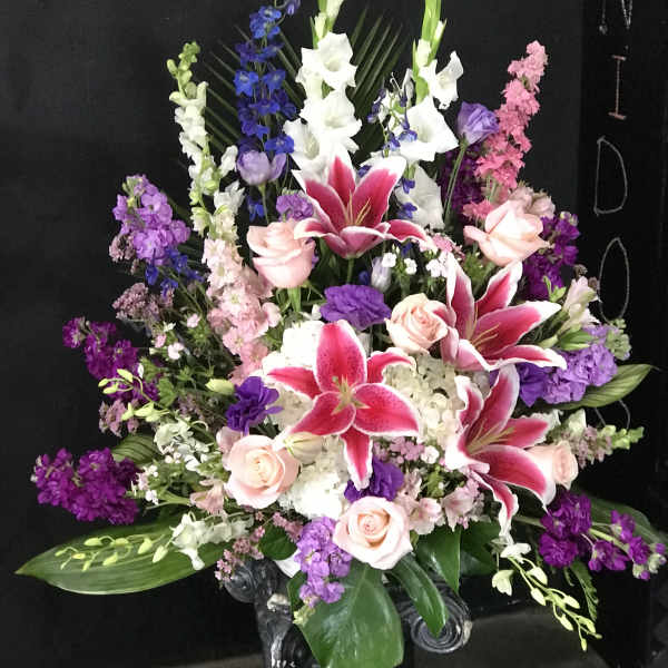Large floral arrangement with pink lilies, roses, and purple flowers
