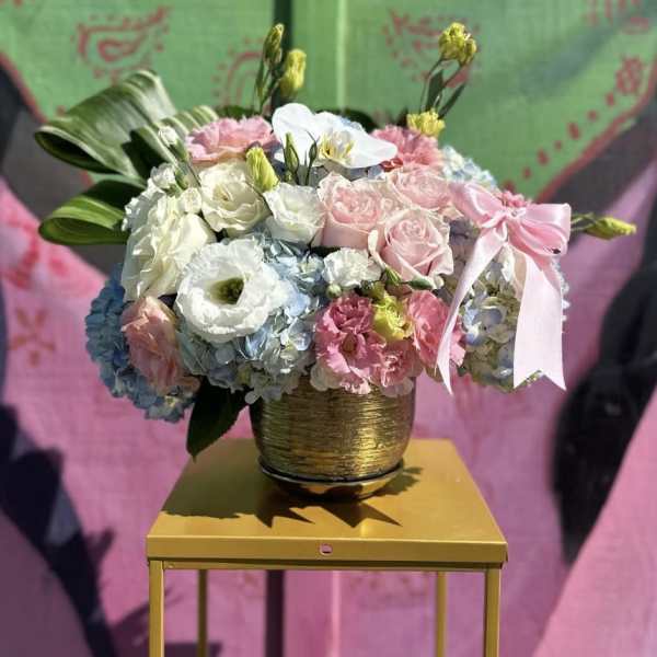 Mixed pastel flower arrangement in a gold pot with a pink ribbon