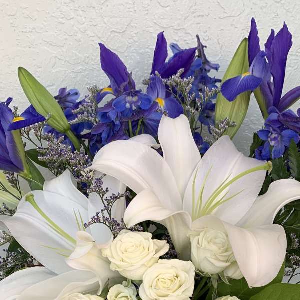 White lilies and roses with blue-purple iris flowers in a bouquet