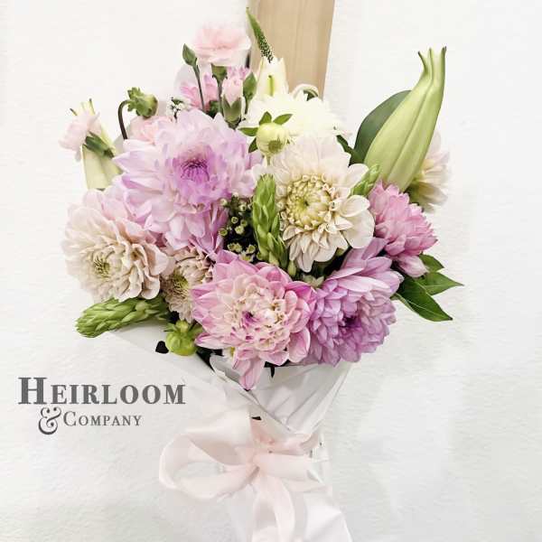 Bouquet of pink and white dahlias wrapped in white paper with a ribbon